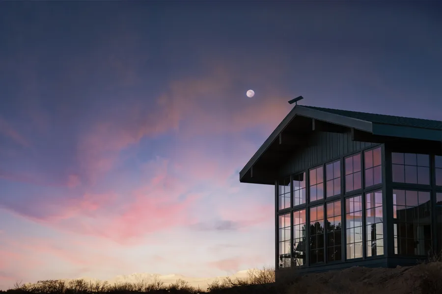 A Starlink dish mounted on the roofline of a house at dusk